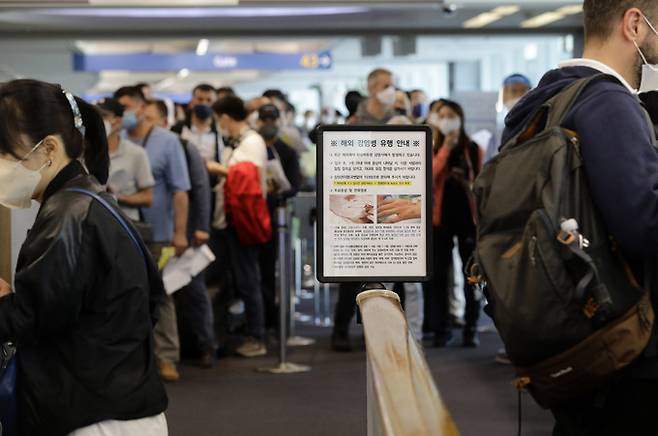 27일 오전 인천국제공항 제1터미널 입국장에서 해외 입국자들이 검역을 받기 위해 대기하고 있다. 입국자들 앞에 원숭이두창 관련 안내문이 세워져있다. 인천공항=뉴스1