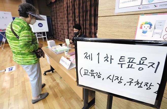제8회 전국동시지방선거가 열린 1일 오전 서울 서대문구 홍은2동 주민센터에 마련된 투표소를 찾은 유권자가 투표용지를 받고 있다. /연합뉴스