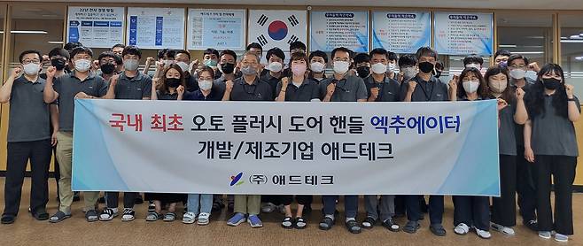 애드테크 임직원들이 오토 플러시 도어 핸들 액츄에이터 국산화 성공 기념 촬영을 하고 있다 [애드테크 제공]