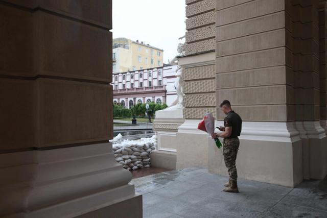 지난 17일 공연 전 꽃을 든 우크라이나 군인이 오페라극장 앞에서 서 있다. 오데사=AFP 연합뉴스