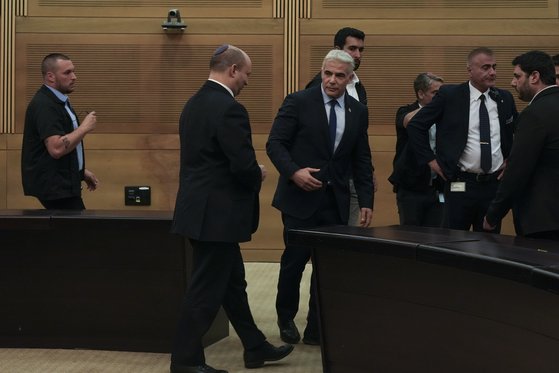 나프탈리 베네트(왼쪽) 이스라엘 총리가 20일(현지시간) 예루살렘의 크네세트(의회)에서 야이르 라피드 외무장관과 함께 연정 해체 성명을 발표하고 퇴장하는 모습. [AP=뉴시스]