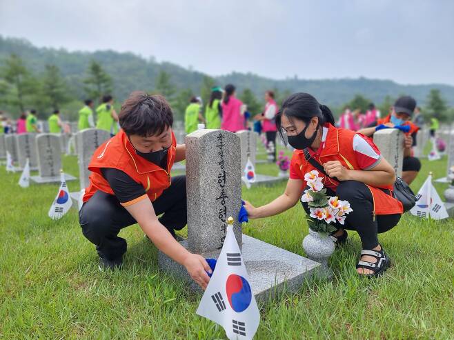 /국민의힘 지성호 의원실 제공   25일 국립서울현충원을 찾은 탈북민 봉사활동 단체 회원들이 참전용사의 묘비를 닦고 있다.