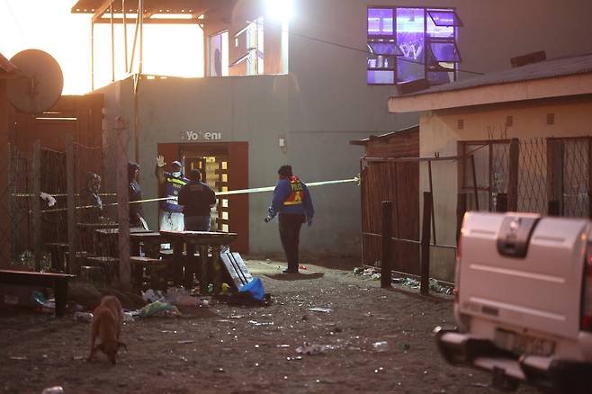 남아프리카공화국 경찰과 법의학자들이 26일(현지시간) 남아공 이스트런던 해안가 타운십의 술집에서 약 20명의 젊은이들이 사망한 현장에서 조사를 하고 있다. [EPA=연합뉴스]