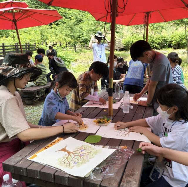 ◇두나무 임직원 및 가족들이 봉사활동을 마치고 진행된 환경교육 프로그램에서 화학 물감 없이 자연을 이용해 그림을 그리고 있다. 사진제공=두나무