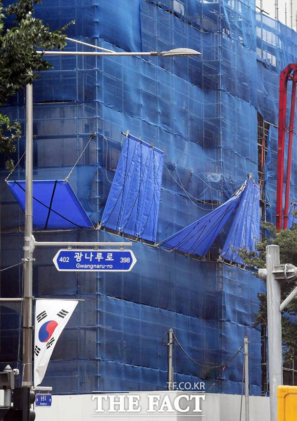 한 공사 현장에 안전 펜스가 강풍으로 벌어지며 위태롭게 매달려 있다.