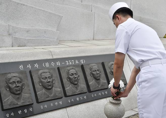 해군 장병이 제2연평해전 전적비 아래 당시 전사한 여섯 용사의 부조상에 헌화하고 있다. 참전 유공자 권기형씨는 화상 인터뷰에서 전투 이후 치료 도중 세상을 떠난 고(故) 박동혁 병장과의 인연을 떠올리며 안타까운 심경을 드러냈다. (해군 제공)