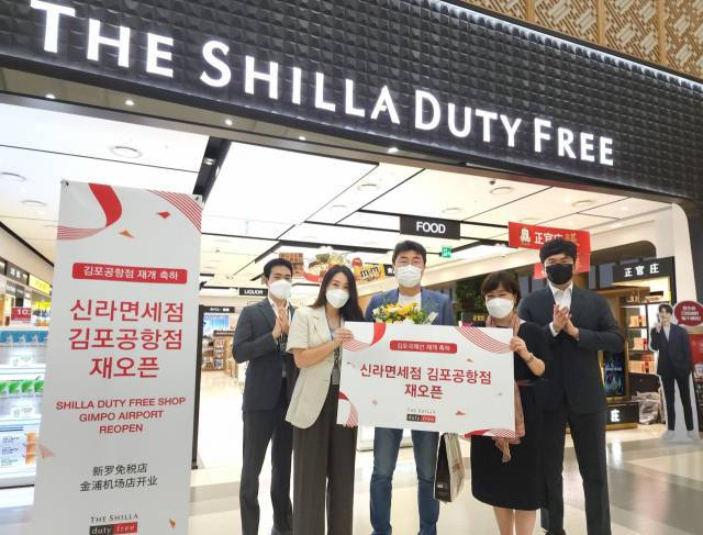 신라면세점 김포국제공항점이 코로나19로 인해 영업을 중단한지 2년 3개월 만인 29일 재오픈했다.신라면세점 장애리 김포공항점장(오른쪽 두번째)이 재오픈 첫 구매 고객(오른쪽 세번째)에게 꽃다발과 함께 기념품을 선물로 증정하고 기념촬영을 하고 있다./사진 제공=신라면세점