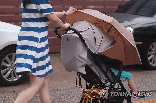 '비 맞으면 안돼' (서울=연합뉴스) 류영석 기자 = 장마가 계속되는 29일 오후 서울 충정로을 지나던 한 시민이 비가 내리자 우산을 아이에게 씌워주고 있다. 2022.6.29 ondol@yna.co.kr