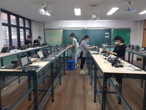 ▲경남교육청이 스마트 단말기 재배포 작업을 위해 한 사업자에 대여해준 창원 내서중학교 내 폐쇄 별관 교실에서 아르바이트생들이 죽 늘어선 수십대의 노트북을 오가며 작업을 하고 있다.