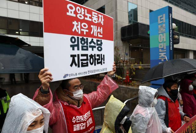 지난해 11월 서울 여의도 민주당사 앞에서 열린 요양보호사 처우개선 및 위험수당 지급 촉구 기자회견에서 전국요양서비스노동조합원이 관련 내용이 적힌 손 피켓을 들고 있다. 연합뉴스