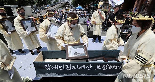 [서울=뉴시스] 백동현 기자 = 1일 오전 서울 용산구 삼각지역 인근에 열린 발달·중증장애인 참사 T4장례식에서 유족들이 희생자의 액자를 관에 넣는 입관식을 하고 있다. 2022.07.01. livertrent@newsis.com