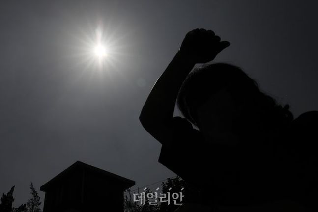 서울 종로구의 한 거리에 시민이 햇빛을 손으로 가리며 이동하고 있다. ⓒ데일리안