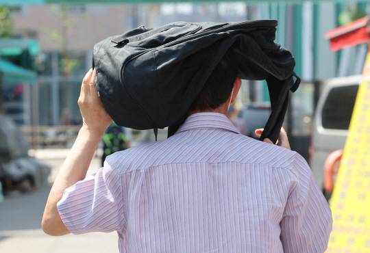 폭염이 이어진 3일 서울의 한 재래시장을 지나가는 시민이 배낭으로 햇빛을 가리고 있다. 연합뉴스