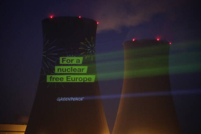 독일 북부 에머탈에 있는 그론데 원자력 발전소의 냉각탑에 2021년 12월30일(현지시각) 환경단체인 그린피스 회원들이 \"원자력 없는 유럽을 위하여\"라는 구호를 조명으로 비추고 있다. 독일은 31일자로 에메르탈 원전을 포함해 모두 3개 원전의 가동을 중단했다. EPA=연합뉴스