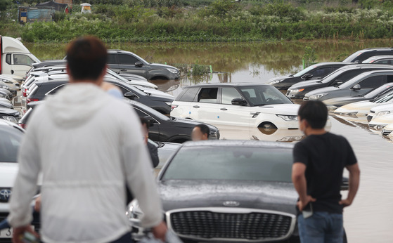 Cars being submerged in water after a sudden rainfall at a parking lot in Suwon on June 30. [NEWS1]