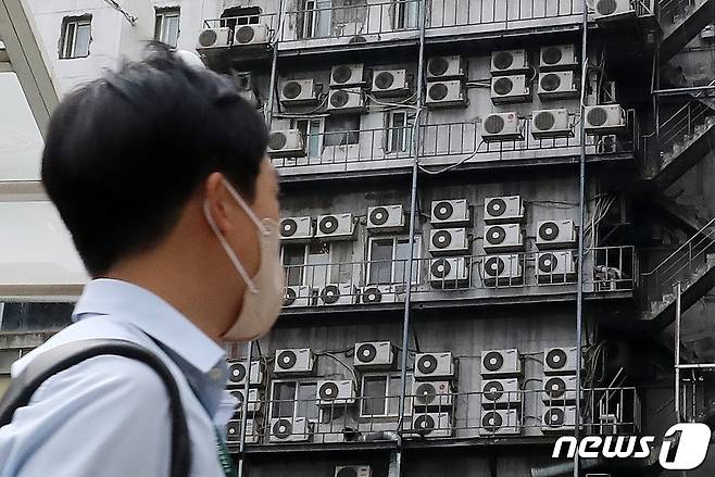 전국에 때이른 폭염이 지속되는 4일 서울 시내 한 건물 외벽에 가득 매달린 에어컨 실외기 앞으로 시민이 지나가고 있다.  2022.7.4/뉴스1 © News1 박세연 기자