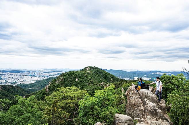 삼성산 정상은 시설물의 철조망 바깥에 있다. 뒤로 보이는 봉우리는 국기봉.