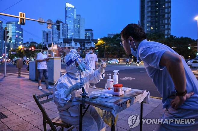 '노래방발 집단감염'에 코로나 검사 나선 상하이 시민 (상하이 AFP=연합뉴스) 5일 밤 중국 상하이 징안구의 한 주거 지역 인근 거리에서 의료인이 코로나19 검사를 위해 한 남성의 검체를 체취하고 있다. 두 달 넘게 봉쇄됐던 상하이에서 노래방에서 시작된 코로나19 집단 감염이 발생해 도시 전체 차원의 코로나19 전수 검사가 진행되면서 다시 긴장이 고조되고 있다. 2022.7.6 leekm@yna.co.kr