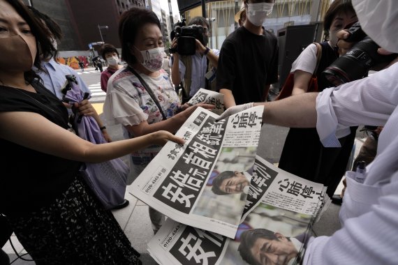 8일 일본 도쿄에서 시민들이 아베 신조 전 총리가 총격을 당했다는 내용의 호외를 받아들고 있다. AP뉴시스
