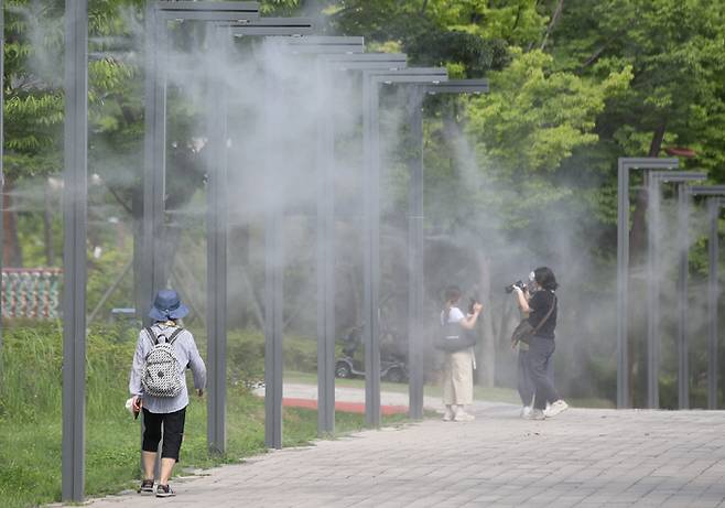 본격적인 더위가 시작되는 소서인 7일 부산 부산진구 부산시민공원 쿨링포그 아래에서 시민들이 더위를 피해 지나가고 있다.   뉴스1