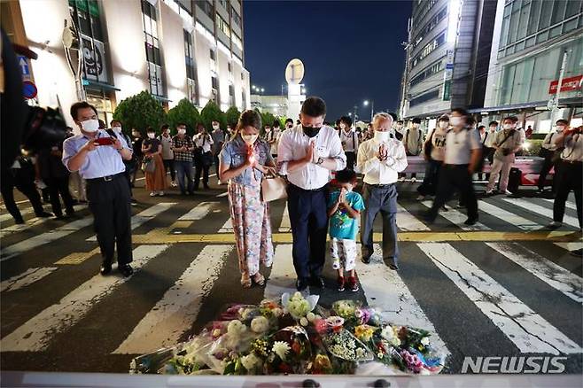 [나라(일본)=AP/뉴시스]지난 8일 밤 아베 신조 전 일본 총리가 총격을 당한 나라현의 현장에 마련된 임시 헌화대에서 시민들이 추모하고 있다.  아베 전 총리는 이날 오전 나라시에서 가두연설 중 총격을 받고 병원으로 이송됐으나 사망했다. 2022.07.09.