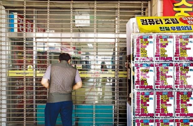 < 결국 못 버티고… > 3일 서울 용산구 선인상가 앞에서 한 시민이 문 닫힌 조립 PC 상가 안을 들여다보고 있다. 인근 부동산중개업소에 따르면 최근 두 달 동안에만 이곳 상인들이 내놓은 점포가 30개를 넘었다.   김병언 기자