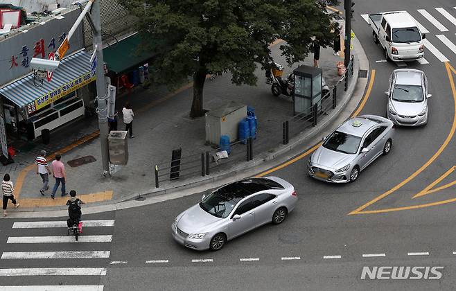 [서울=뉴시스] 백동현 기자 = 횡단보도 앞 일시정지 의무를 확대하는 등 보행자 보호의무가 강화된 도로교통법 시행 첫날인 12일 오후 서울 시내 한 횡단보도에서 우회전하는 차량이 보행자의 횡단을 기다리고 있다. 2022.07.12. livertrent@newsis.com