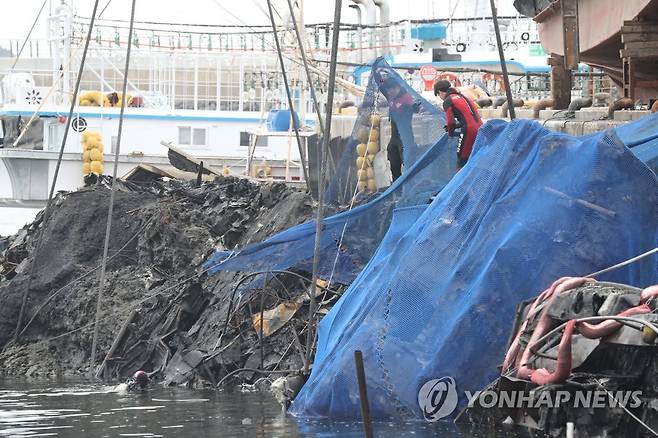 유실 방지망 씌우는 해경 (제주=연합뉴스) 박지호 기자 = 12일 오후 제주시 한림항에서 해경 구조대원들이 지난 7일 불이 난 한림 선적 근해채낚기 어선 A호(29t) 인양 과정에서 유실 방지망을 씌우고 있다. 2022.7.12 jihopark@yna.co.kr