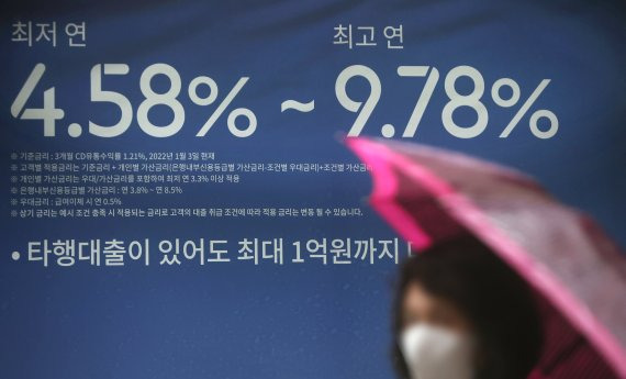 한국은행이 사상 처음 빅스텝(기준금리 0.50%p 인상)을 단행한 13일 서울 시내 은행 외벽에 붙은 대출금리 안내판 앞을 한 시민이 지나가고 있다. 연합뉴스