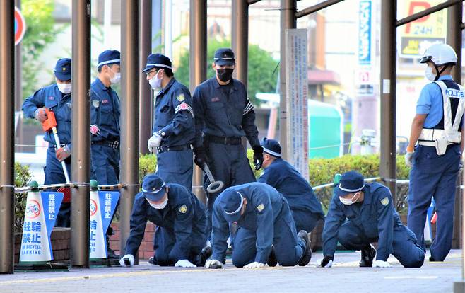 아베 신조 전 총리 암살 사건을 수사 중인 일본 나라현 경찰본부 감식원들이 13일 사건 현장인 나라시 야마토사이다이 일대에서 무릎을 끓고 이동하며 총알과 탄흔을 찾고 있다. 아사히신문 제공