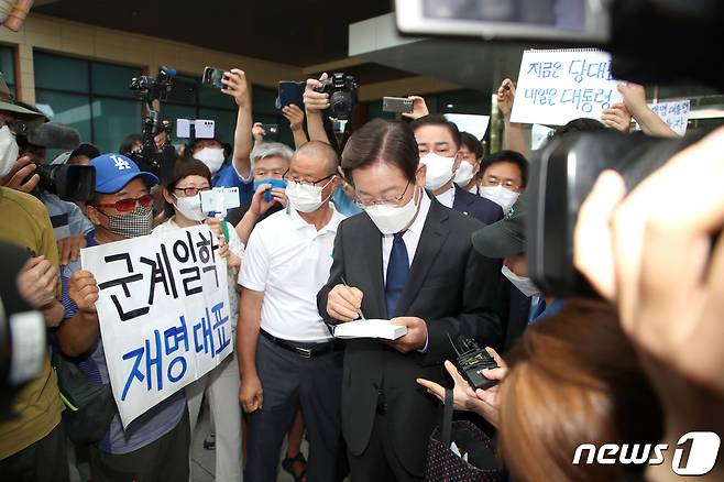 이재명 더불어민주당 국회의원이 17일 서울 여의도 국회 소통관에서 더불어민주당 8.28 전당대회 당대표 출마를 선언을 마친 후 회견장을 나서며 한 지지자에게 사인을 해주고 있다. (공동취재) 2022.7.17/뉴스1 © News1 허경 기자