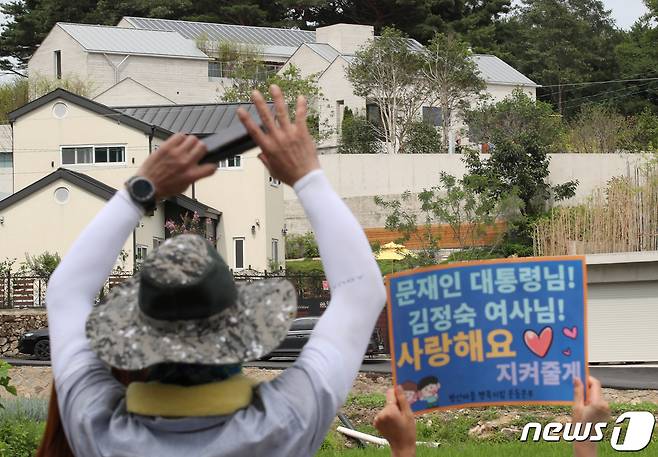 17일 경남 양산 하북면 평산마을 문재인 전 대통령 사저앞에서 열린 문 전 대통령 규탄 집회와 평산마을 일상회복 기원집회가 동시에 진행되는 가운데 평산마을 일상회복 기원집회자가 문 전 대통령 향해 손을 흔들고 있다. 2022.7.17/뉴스1 © News1 김영훈 기자