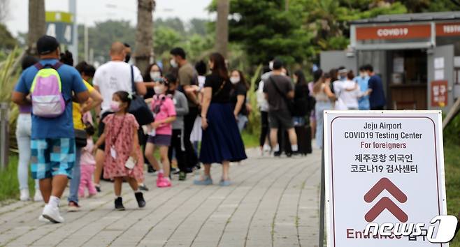 14일 오후 제주국제공항 주차장에 설치된 외국인 코로나19 검사센터에 이날 제주에 도착한 몽골인 관광객들이 줄서서 기다리고 있다. 한국공항공사 제주본부는 제주공항 국제선 재개 및 최근 코로나 확산에 대비해 이날부터 공항 내에서 코로나 검사센터를 운영하고 있다.2022.7.14/뉴스1 © News1 고동명 기자