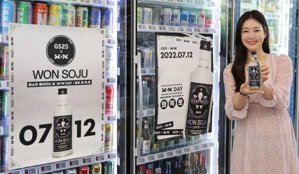 GS25 모델이 원소주 스피릿 출시 홍보 포스터 옆에서 포즈를 취하고 있다. [사진 제공 = GS리테일]