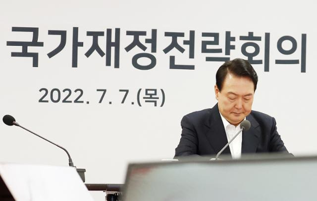 윤석열 대통령이 7일 충북 청주시 충북대학교에서 열린 '2022 국가재정전략회의'에서 자료를 살펴보고 있다. 정부는 이 회의에서 "역대 최고 수준의 강력한 지출 구조조정으로 임기 말 국가채무비율을 50%대 중반으로 관리하겠다"고 밝혔다. 연합뉴스