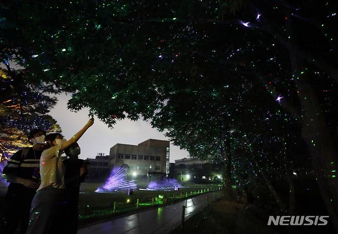 [서울=뉴시스] 고승민 기자 = 19일 청와대 일원에서 열린 '청와대 한여름 밤의 산책' 프레스 투어에서 참가자들이 녹지원의 레이저 반딧불을 관람하고 있다. 본행사는 20일부터 내달 1일까지 열린다. 2022.07.19. kkssmm99@newsis.com