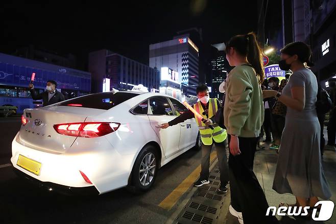 서울시와 서울개인택시조합이 심야 승차난 해소를 위해 승차지원단을 운영하고 있다. 서울 서초구 강남역 인근에서 승차지원단이 택시 임시승차대를 설치하고 시민들의 택시 탑승을 돕고 있는 모습.2022.5.12/뉴스1 © News1 이광호 기자