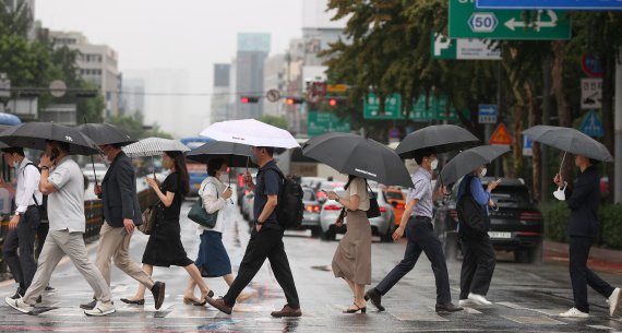 전국 곳곳 비 소식이 예보된 21일 오전 서울 종로구 광화문네거리에서 시민들이 우산을 쓴 채 이동하고 있다./연합뉴스