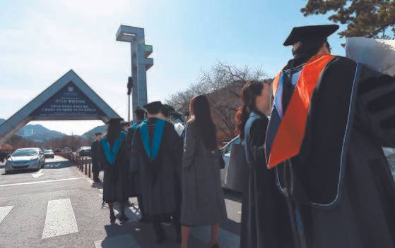 지난 2월 서울 관악구 서울대학교에서 학위를 받은 학생들이 학교 정문을 배경으로 사진을 찍기 위해 줄지어 차례를 기다리고 있다. 연합뉴스