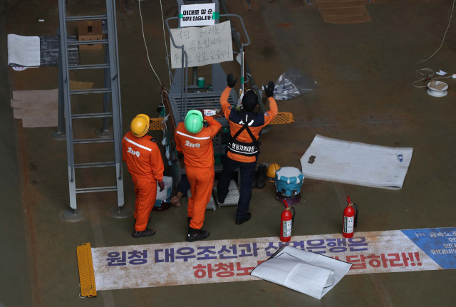 ▲대우조선해양 하청 노사협상이 극적으로 타결된 22일 오후 경남 거제시 아주동 대우조선해양 옥포조선소 내 1독에서 대우조선 소방대원이 철 구조물에서 농성 중인 유최안 금속노조 거제통영고성 조선하청지회 부지회장을 살펴보고 있다. ⓒ연합뉴스