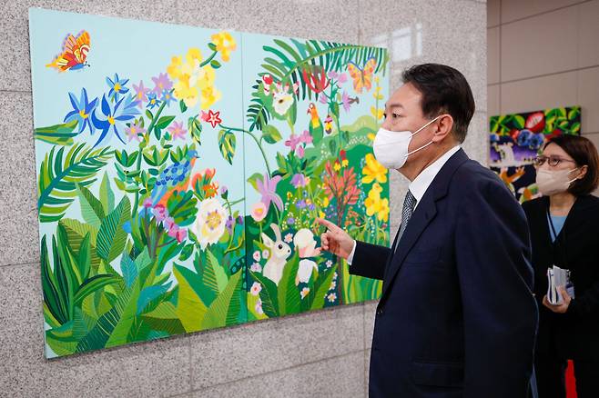 윤석열 대통령이 25일 오전 용산 대통령실에서 출근길 약식 기자회견(도어스테핑)을 마친 뒤 그림을 둘러보고 있다. 이날 대통령실 1층 양옆 벽면에는 발달장애 작가들의 작품 15점이 처음 전시됐다. /뉴스1