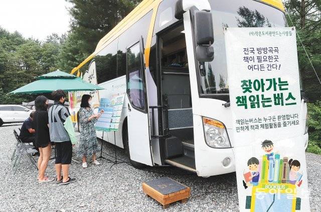 충북 제천시 스테리움 제천 캠핑장의 ‘책 읽는 버스’ 앞에서 23일 캠핑장 이용객들이 독서 퀴즈에 참여하고 있다. 제천=안철민 기자 acm08@donga.com