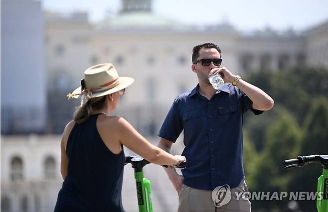 미국 워싱턴DC에서 스쿠터를 타다 멈춰서서 물을 마시는 사람들 [AFP=연합뉴스]