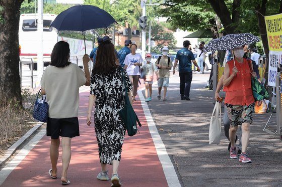 서울 전역에 폭염경보가 내린 29일 시민들이 서울 용산구 전쟁기념관에서 양산을 쓰고 나무그늘 밑으로 걷고 있다. 연합뉴스