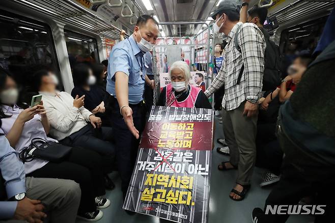 [서울=뉴시스] 김진아 기자 = 전국장애인차별철폐연대가 1일 오전 서울 종로구 5호선 광화문역에서 열린 '제34차 출근길 지하철탑니다'에서 지하철 승하차 시위를 하고 있다. 전장연은 내년도 본예산에 장애인 권리 예산 반영, 장애인 권리 4대 법률 제개정, 서울시의 장애인 탈시설 지원 조례 재정 등을 요구하며 지난해 12월부터 출근길 지하철 선전전을 진행하고 있다. 2022.08.01. bluesoda@newsis.com