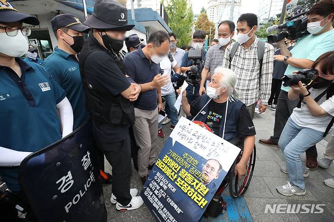 [서울=뉴시스] 조수정 기자 = 전국장애인차별철폐연대(전장연) 박경석 상임공동대표 등이 지난달 25일 오전 서울 종로경찰서 앞에서 자진출석을 하기 위해 출석요구서를 보여주며 경찰과 대화하고 있다. 이날 전장연은 "김광호 서울경찰청장이 지구 끝까지 찾아가 사법처리하겠다고 했고 출석요구서에 따라 자진출석했으나 장애인 편의시설 설치조차 돼 있지 않아 장애인·노인·임산부 등의 편의증진 보장에 관한 법률 위반"이라며 조사를 미뤘다. 종로경찰서 측은 1층에서 조사받도록 준비했다고 했지만 편의시설은 오래된 건물이라 설치돼 있지 않다고 밝혔다. 2022.07.25. chocrystal@newsis.com