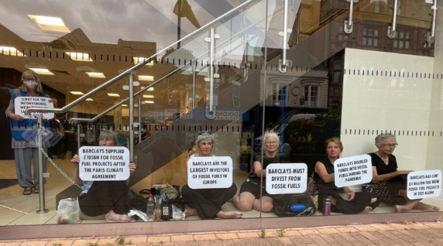 크리스천 기후행동(CCA) 소속 할머니들이 지난달 말 영국 런던에 있는 바클리즈 은행 안 로비에서 몸에 체인을 두른 채 ‘바클리즈는 화석 연료에 대한 투자를 멈춰야 한다’는 등의 내용이 담긴 플랜카드를 들고 시위하고 있다. CCA 제공