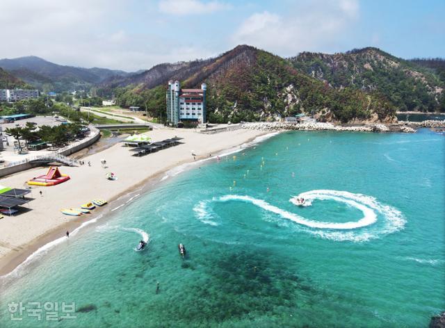 에메랄드 빛 눈부신 나곡해변에서 피서객들이 물놀이를 즐기고 있다. 해변 뒷산에는 산불의 생채기가 고스란히 남아 있다.