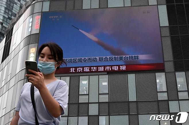 4일(현지시간) 중국 베이징에서 대만을 상대로 한 대규모 군사훈련에 대한 뉴스가 나오는 스크린 앞을 한 여성이 걸어가고 있다. ⓒ AFP=뉴스1 ⓒ News1 박기현 기자