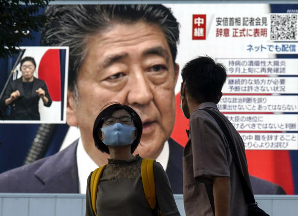 일본 도쿄 행인들이 지난 28일 아베 신조 총리가 사임을 발표하는 중계방송을 지켜보고 있다. 아베 총리가 이날 기자회견에서 건강 악화를 이유로 사퇴한다고 밝히면서 후임 총리에 관심이 쏠리고 있다.도쿄 EPA 연합뉴스